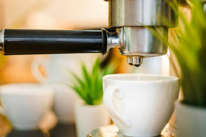 Espresso pouring from a portafilter into a white cup